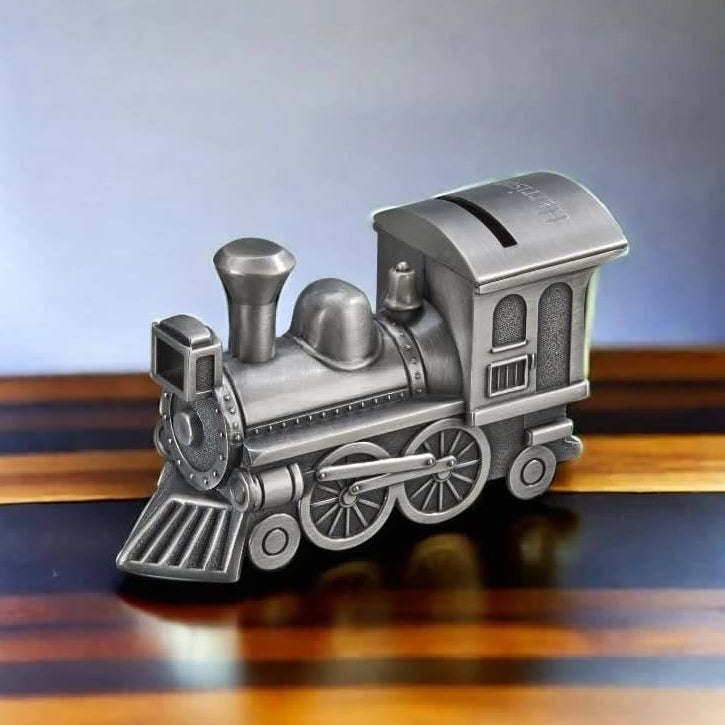 A metallic silver train-shaped money box or piggy bank displayed on a polished wooden surface against a soft gray gradient background.