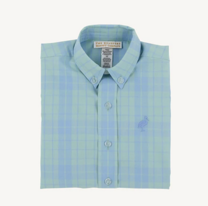 A folded light blue and pale green plaid button-down shirt by The Marshes, featuring a small embroidered bird logo on the chest, set against a plain off-white background.