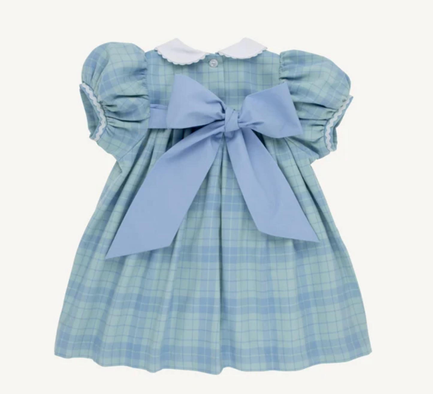 A baby girl's light blue and white plaid dress with puffed sleeves, a white ruffled collar, and a large light blue bow at the back, shown against a plain off-white background.