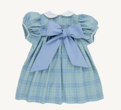 A baby girl's light blue and white plaid dress with puffed sleeves, a white ruffled collar, and a large light blue bow at the back, shown against a plain off-white background.
